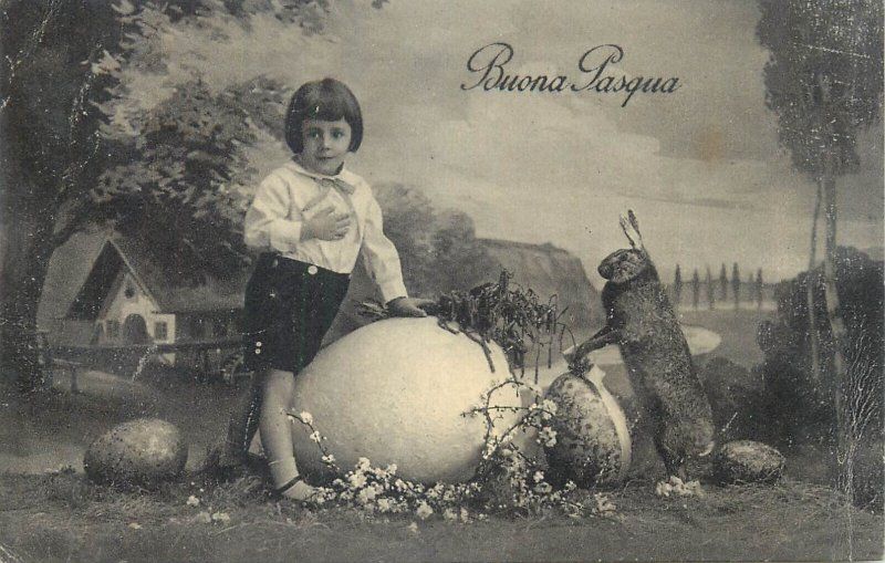antique illustrated postcard of a small boy, giant egg, and bunny. reads “buona pasqua”