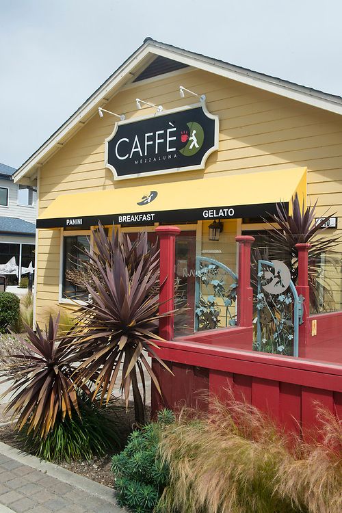 view of caffe mezzaluna from outside. yellow buiding with greenery and red deck area